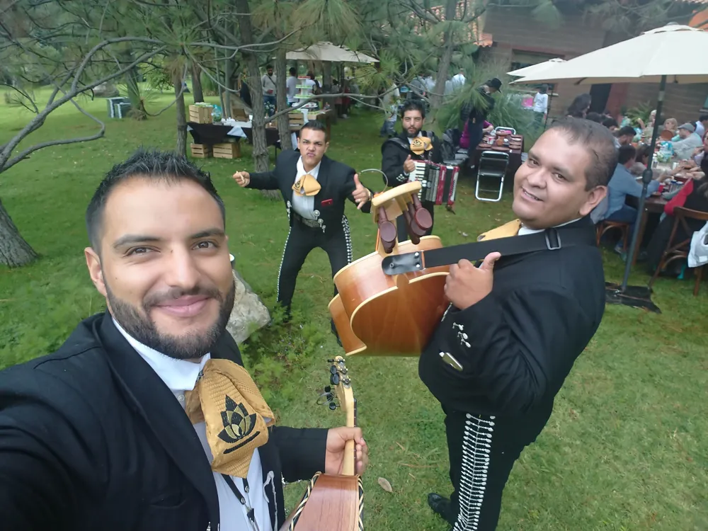 Integrantes de Mariachi Jalisco Es Tradición en traje negro durante una serenata al aire libre