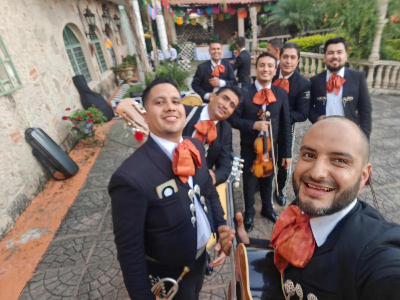 Integrantes de Mariachi Jalisco Es Tradición en traje de charro negro y moño rojo en un patio de hacienda